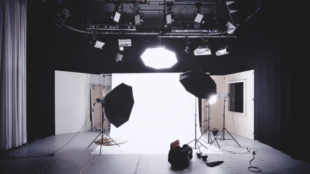 Estudio de fotografía con focos y fondo blanco.